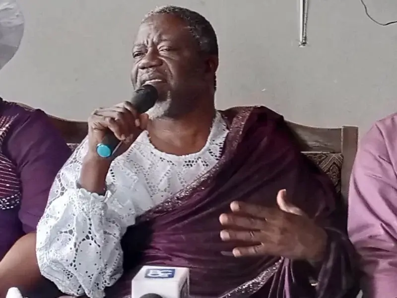 Man in traditional attire speaking into microphone.
