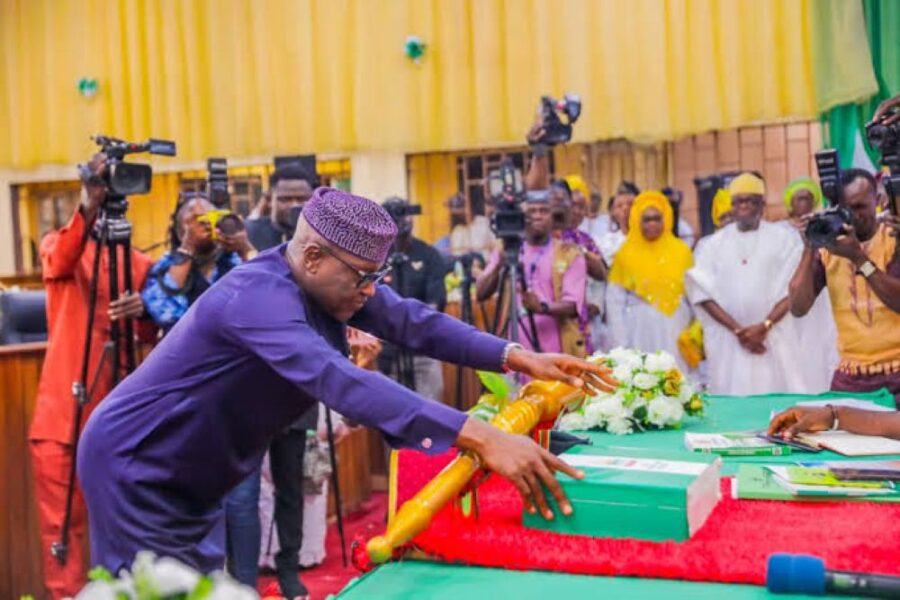 Man in purple attire placing a ceremonial mace on table.