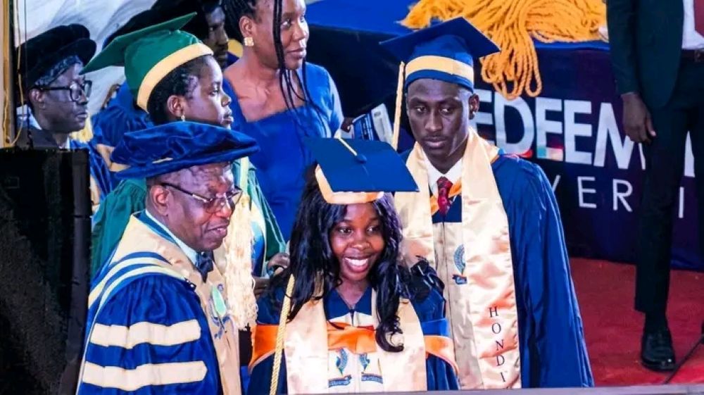 Smiling graduates and faculty in academic regalia at a ceremony.