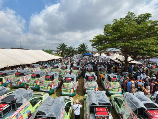Campaign vehicles and a large crowd at a political rally.