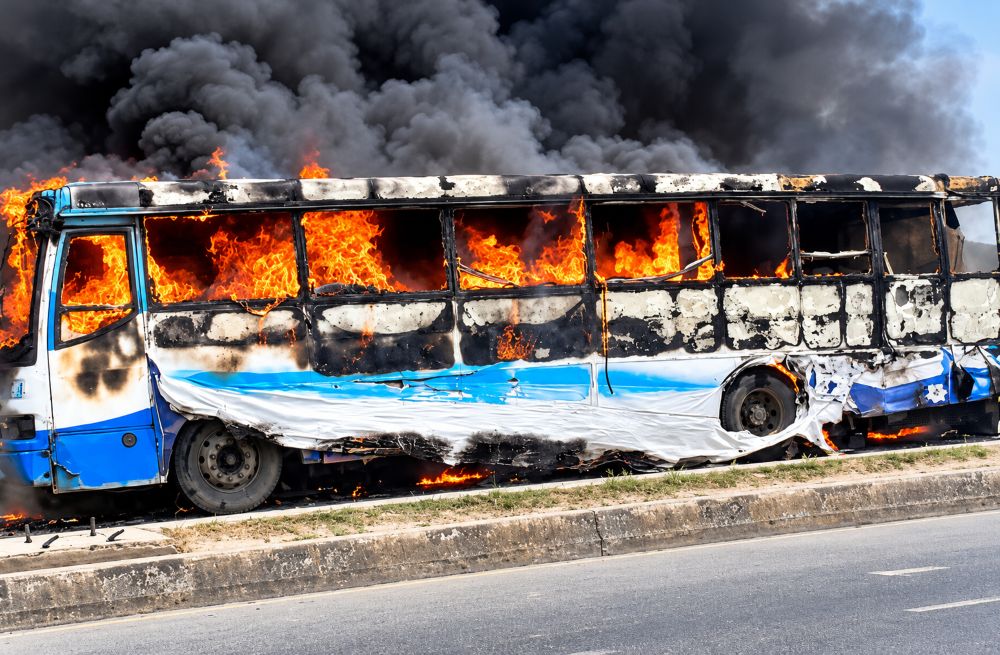 A blue and white bus engulfed in intense orange flames.