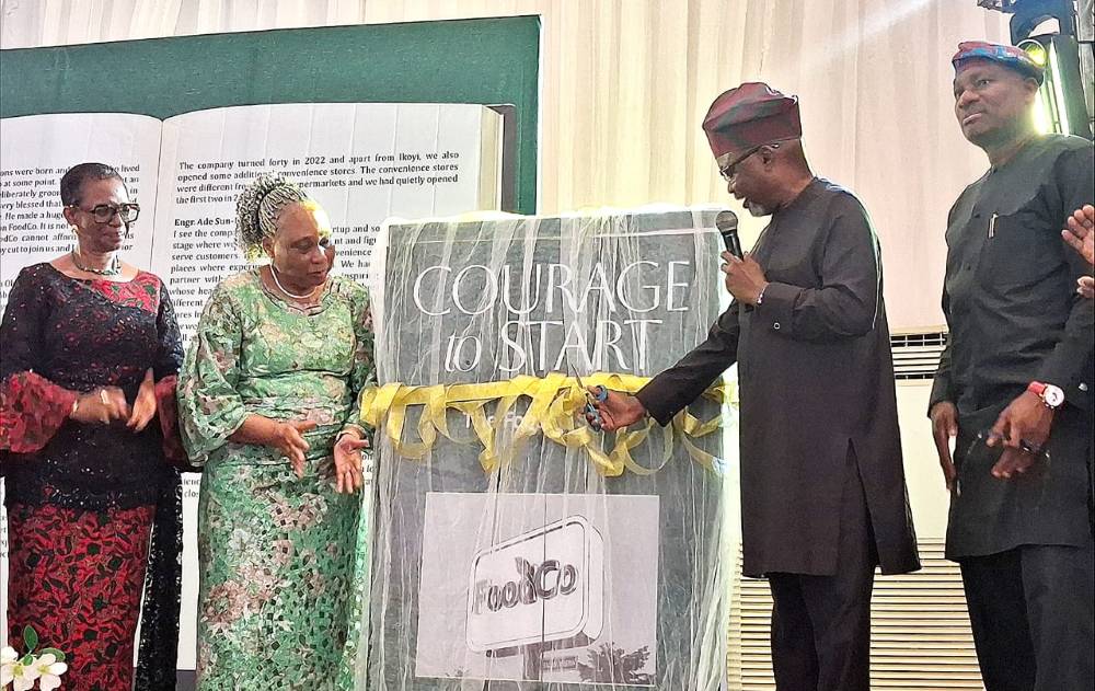Man cutting a ribbon for 'Courage to Start' book unveiling.